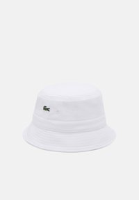 Weißer Baumwoll-Bucket-Hut mit strukturiertem Finish, einem grünen gestickten Krokodil-Logo an der Seite und einem leicht gebogenen Schirm.