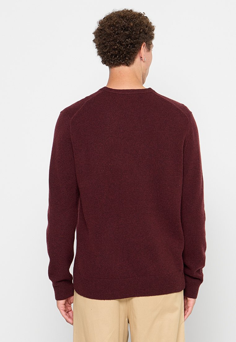 Pull bourgogne en tissu doux, avec un col rond, des manches longues et un ourlet côtelé. Texture lisse avec un dos sans couture.