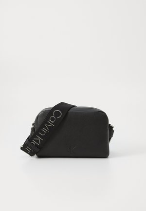 Sort faux læder crossover taske med en tekstureret overflade, sølv hardware og en aftagelig rem med "Calvin Klein" logo.