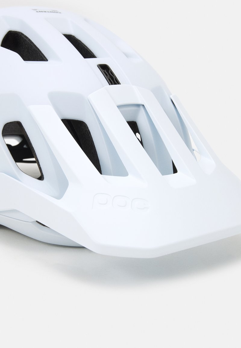 Weißer, belüfteter Fahrradhelm mit einem Visier und schwarzer Innenpolsterung, mit dem eingravierten Markensymbol auf der Vorderseite.