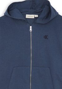 Felpa con zip color blu navy realizzata in tessuto liscio, dotata di cappuccio con cordini, tasche frontali e logo ricamato "ck" sul petto.