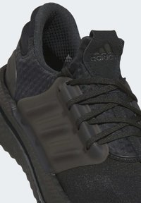 Black athletic shoe with a textured upper, reinforced heel, flexible sole, and lacing system. Features logo and subtle design accents.