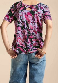 Blommig kortärmad topp med mörkgrön bakgrund och rosa samt lila blommor, kompletterad med en urtagning på baksidan.