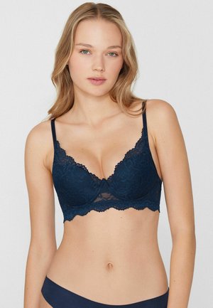 Bralette en dentelle bleu marine avec motifs floraux, panneaux transparents et bords festonnés. Bretelles réglables et design rembourré pour une meilleure mise en forme.