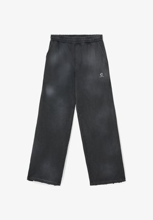 Pantalon noir à coupe ample avec taille élastique, poches latérales et petit logo blanc sur la cuisse supérieure.