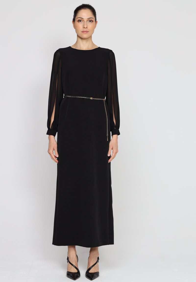 Czarna sukienka z długim rękawem, z przezroczystymi panelami, prosty krój, lekki materiał; posiada wąski pasek z łańcuszkiem.