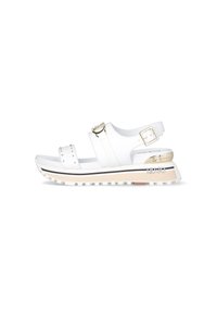 Sandali platform bianchi con due cinturini regolabili, dettagli in metallo dorato, borchie decorative e suola in gomma testurizzata con striscia nera a contrasto.