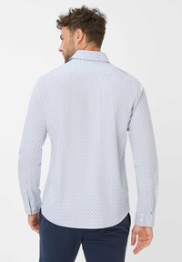 Langsleeve overhemd in lichtblauw met een klein stippenpatroon. Voorzien van een klassieke kraag en knoopsluiting op de mouwen. Zachte stoftextuur.