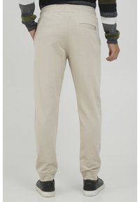 Lys beige joggers lavet af blødt, tekstureret stof med elastisk talje, tapered ben og en enkelt baglomme.