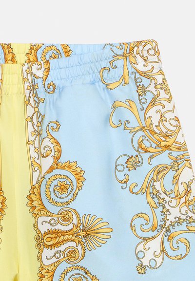 Σύνθεση σορτς με σχέδιο σε ανοιχτό μπλε και κίτρινο, διακοσμημένα με περίτεχνα χρυσά μοτίβα σε μορφή σπειρωμάτων κατά μήκος της ποδόγυρης και της μέσης.