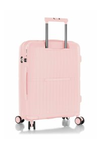 Maleta rígida de color rosa claro con rayas verticales, mango retráctil y cuatro ruedas negras. Cuenta con un cierre y una cerradura de combinación incorporada.