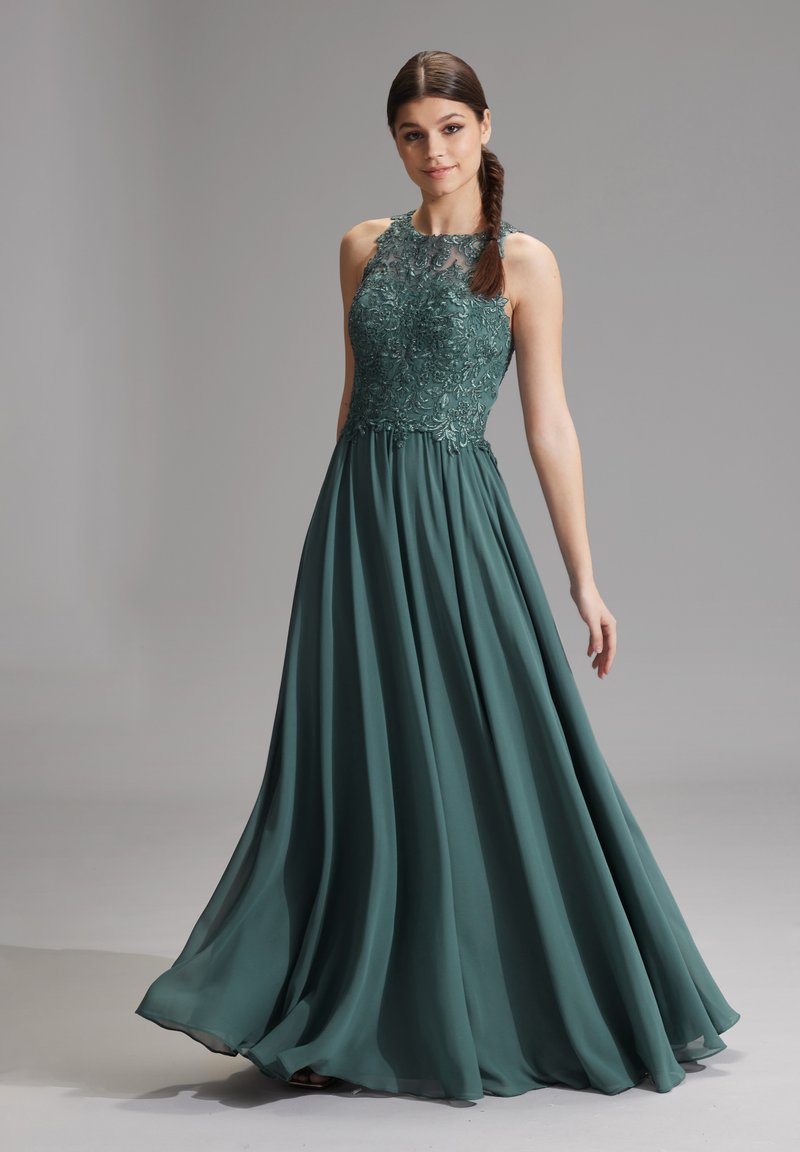 Vestito da sera turchese con un corpetto trasparente e decorato di perline e una gonna ampia e fluida. Presenta un scollo rotondo e dettagli ricamati eleganti.