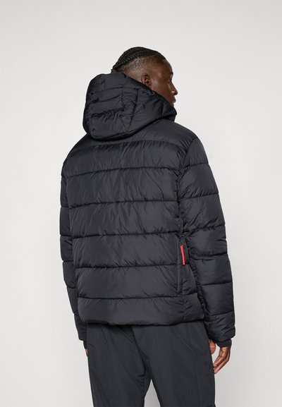 Giacca a vento nera con cappuccio, con un design trapuntato, tasca laterale con zip rossa e polsini elasticizzati per un calore extra.