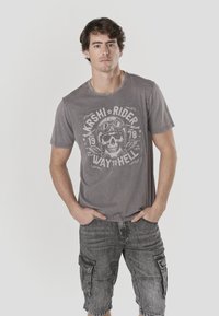 Gray T-shirt featuring a skull graphic with text, paired with dark gray cargo shorts. The fabric appears soft with a casual fit.