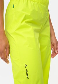 Lime green waterproof pants with an elastic waistband. Features a textured surface, a visible logo in black, and a side pocket.