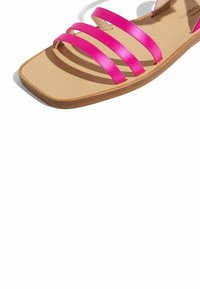 Flache Sandalen mit drei glänzenden rosa Riemen, quadratischer Zehenpartie und einer hellbraunen Innensohle. Sie haben eine glatte Oberfläche und eine dezente braune Sohle.