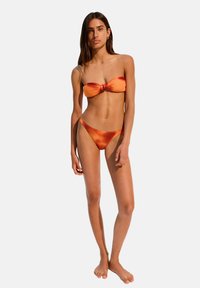 Orange bikini set featuring a bandeau top with a knot detail and low-rise thong bottom. Smooth texture and seamless design.