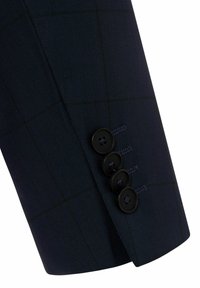 Ärmel eines dunkelblauen Anzugs mit dezentem Karomuster und vier schwarzen Knöpfen in einer Reihe nahe der Manschette.