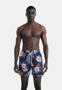 Pantaloni da bagno blu navy con motivo floreale in rosso e bianco, dotati di cintura elastica e cordoncino bianco.