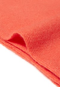 Tessuto a maglia corallo con una superficie morbida e testurizzata, che presenta un bordo piegato e liscio. Il materiale appare caldo e leggero.