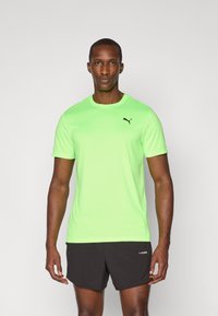 Bright green short-sleeve athletic shirt with a black Puma logo on the chest. Fabric appears smooth and lightweight, suitable for sports.