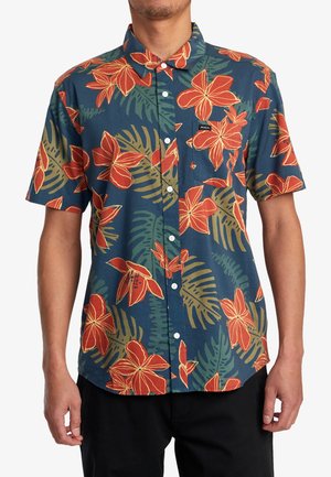 Short-sleeve button-up shirt with a navy background, featuring large red flowers and green foliage patterns. Cotton material with chest pocket.