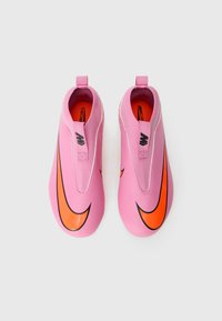 Baskets de sport roses à enfiler avec un swoosh Nike orange, présentant une surface texturée et sans lacets visibles, conçues pour le confort et la performance.