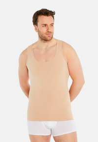 Beige tank top made of soft cotton blend, featuring wide straps and a fitted design, paired with white boxer briefs.