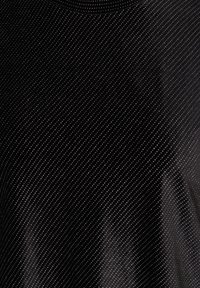 Czarna tkanina z gęstym wzorem małych białych kropek ułożonych po przekątnej, z widocznymi niewielkimi zagnieceniami i fakturą.