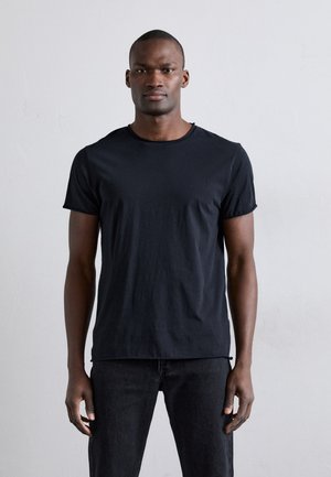 Black short-sleeve t-shirt with a round neckline. Made of soft fabric, it has a fitted shape and a smooth texture. Worn with dark jeans.