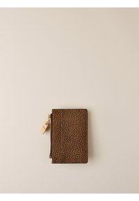 Portafoglio in pelle marrone con texture, dotato di una zip dorata, posato su uno sfondo beige chiaro.