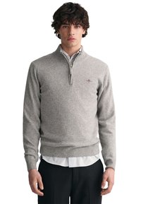 Grauer Pullover mit einem Halbreißverschluss-Kragen, gerippten Bündchen und Saum; aus einem weichen, texturierten Stoff gefertigt; gesticktes Logo auf der linken Brust.