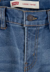 Blå denimjeans med lös tapered passform. Har en knappstängning, bälteslopp och synlig sömnad. Märkesskylten säger "Levi's Loose Taper."