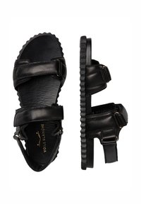 Zwarte leren sandalen met twee verstelbare banden, een gestructureerde zool en ronde randen, met gouden hardware accenten en een plat ontwerp.