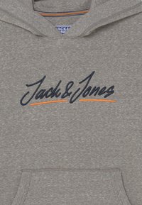 Felpa grigia realizzata in un tessuto morbido, con un grande logo ricamato in blu navy "Jack & Jones" con una sottolineatura arancione. Include una tasca frontale.