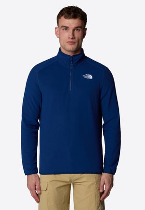 Marineblauwe fleece kwart-rits pullover met lange mouwen en een hoge kraag. Voorzien van een ritssluiting aan de voorkant en een wit logo op de linkerborst.