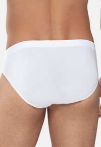 Culotte en coton blanc avec une texture lisse, une ceinture élastique et un design arrière sans couture. Pas de motifs ni de logos visibles.