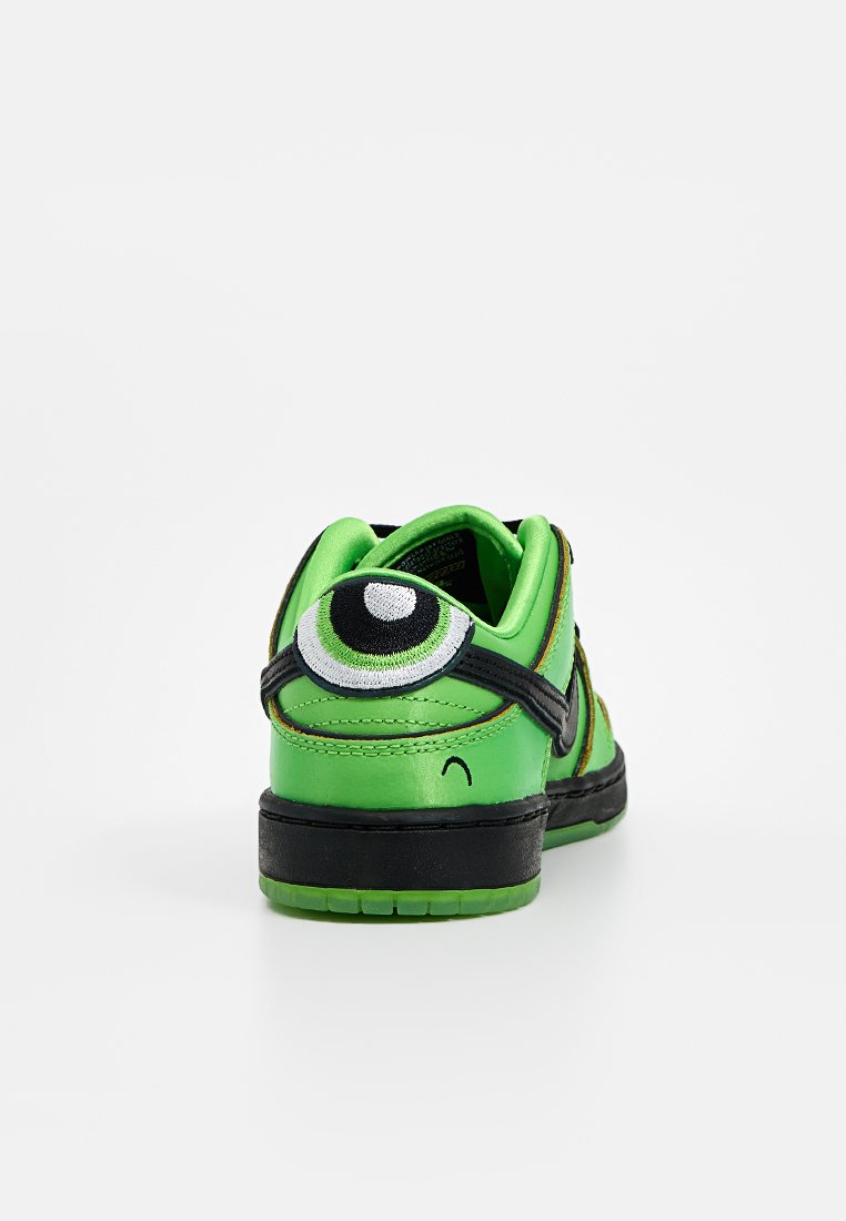 Zapatilla verde con un detalle de ojo cosido en el talón. Presenta una parte superior suave, acentos negros y una suela texturizada.