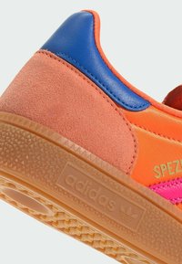 Orange and pink sneaker featuring suede and leather materials, a textured gum sole, and gold “SPEZIAL” branding. Accented with blue detailing.