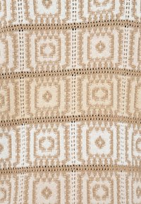 Tissu en maille présentant un motif géométrique beige et crème avec des détails en ajouré, comprenant des carrés et des losanges, design texturé et superposé.