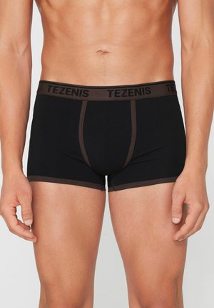 Männlicher Torso trägt schwarze Boxer-Shorts mit dunkelbraunem Besatz und Bund, gebrandet mit "TEZENIS" in schwarzen Buchstaben.