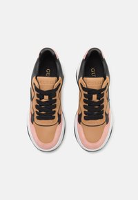 Sneakers i brunt lær med svarte og rosa akenter, med svarte lisser og en teksturert såle, med "GUESS"-logo på tungen.