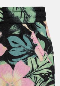 Sorte blomstrete shorts med rosa og grønne tropiske bladmønstre, elastisk livlinje og en liten svart logo på siden.