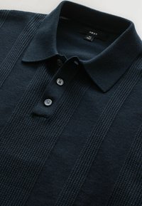Navy blue polo shirt featuring a textured knit pattern with vertical stripes. It has a collar and three buttons at the opening.