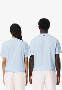 Camisetas de algodón azul claro con mangas cortas, que cuentan con un pequeño logo verde en la parte posterior del cuello. Ambas camisetas son de corte relajado.