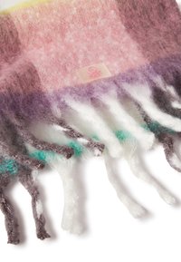 Wielokolorowy wełniany szalik z różowym, fioletowym i zielonym wzorem, z frędzlami na krawędziach oraz małą różową naszywką z logo. Miękka faktura.