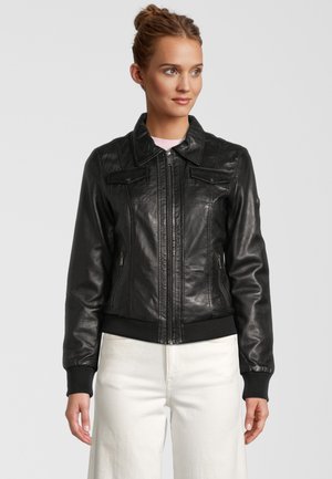 Schwarze Lederbomberjacke mit Reißverschluss vorne, gerippten Bündchen und Saum sowie zwei Brusttaschen. Modell trägt hellfarbene Hosen.