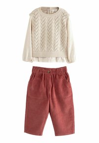 Cremefarvet strikket sweater med zigzag-mønster og lange ærmer, sammen med røde kordfløjl bukser med elastisk talje og lommer.