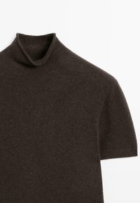 Brun kortärmad polotröja i mjukt tyg, med en vikt krage och slät yta. Designen är enkel med minimal detaljer.