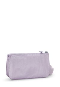 Kleine rechthoekige lavendelkleurige pouch met een ritssluiting aan de bovenkant en een fluffy pompon die aan de ritssluiting aan de zijkant is bevestigd.